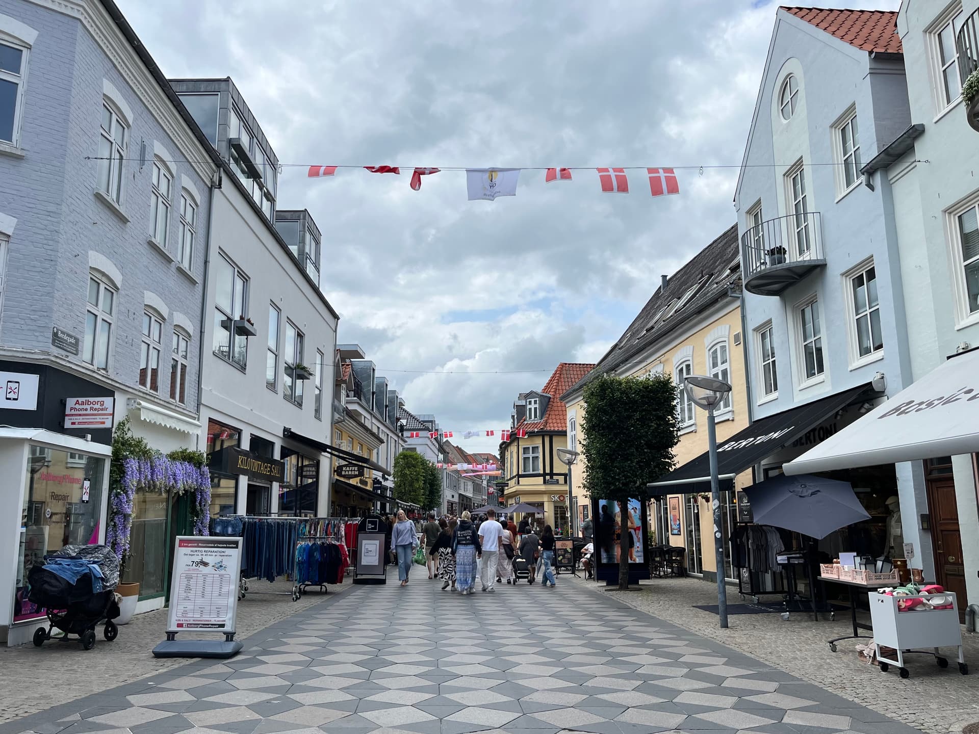 Historische Fußgängerzone in Aalborg mit traditionellen dänischen Gebäuden und Flaggen