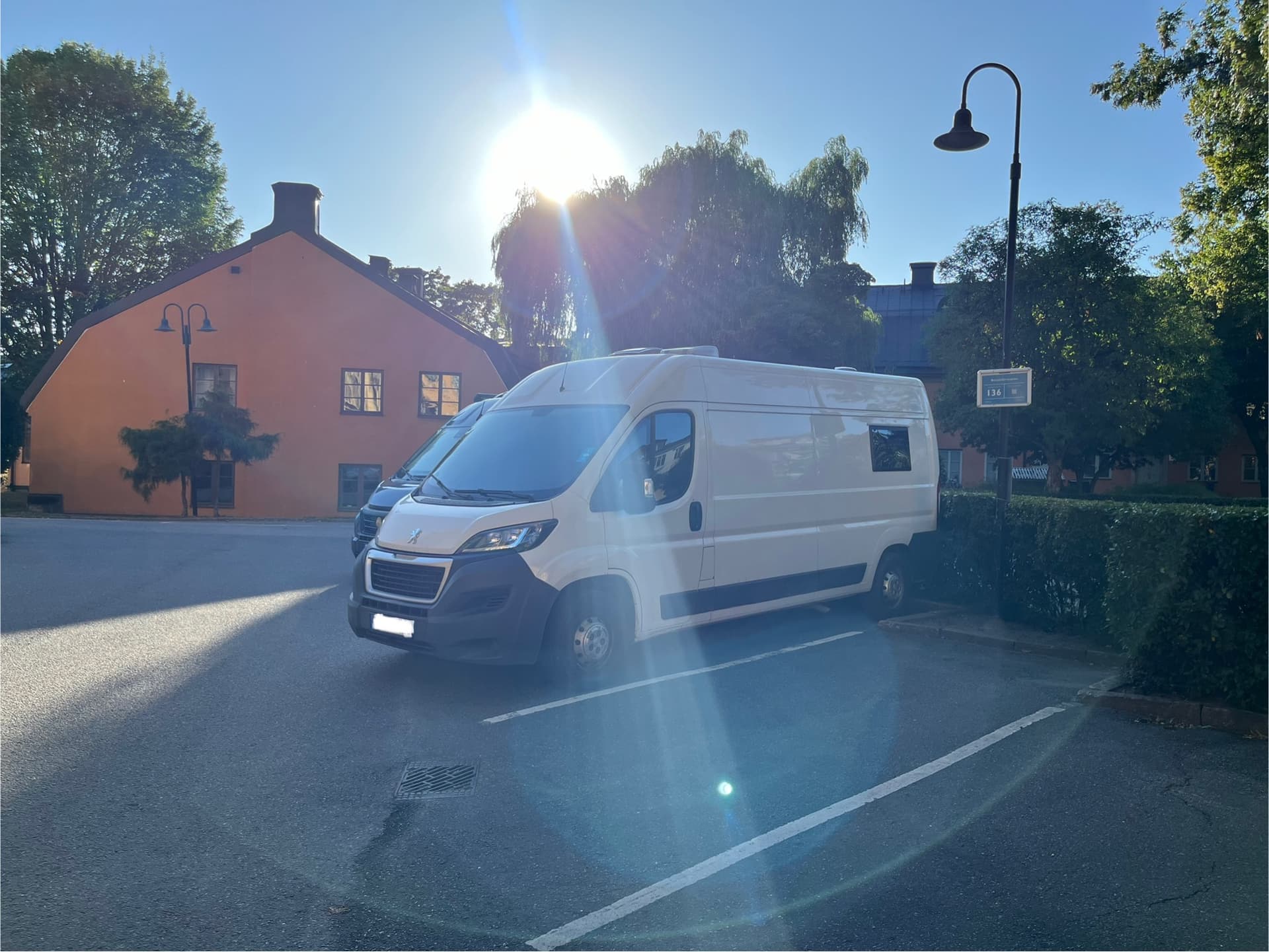 Weißer Peugeot Boxer Campervan vor einem traditionellen orangefarbenen Gebäude in Stockholm bei Sonnenschein