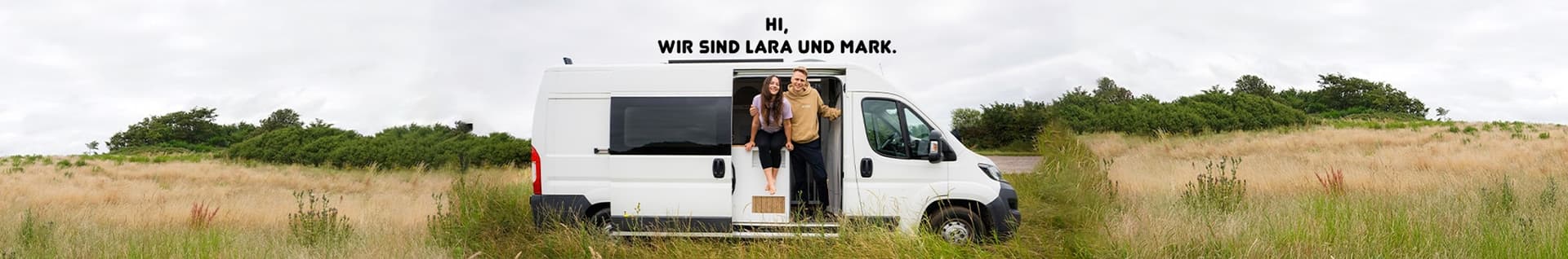 Lara und Mark vor ihrem Campervan in der Natur