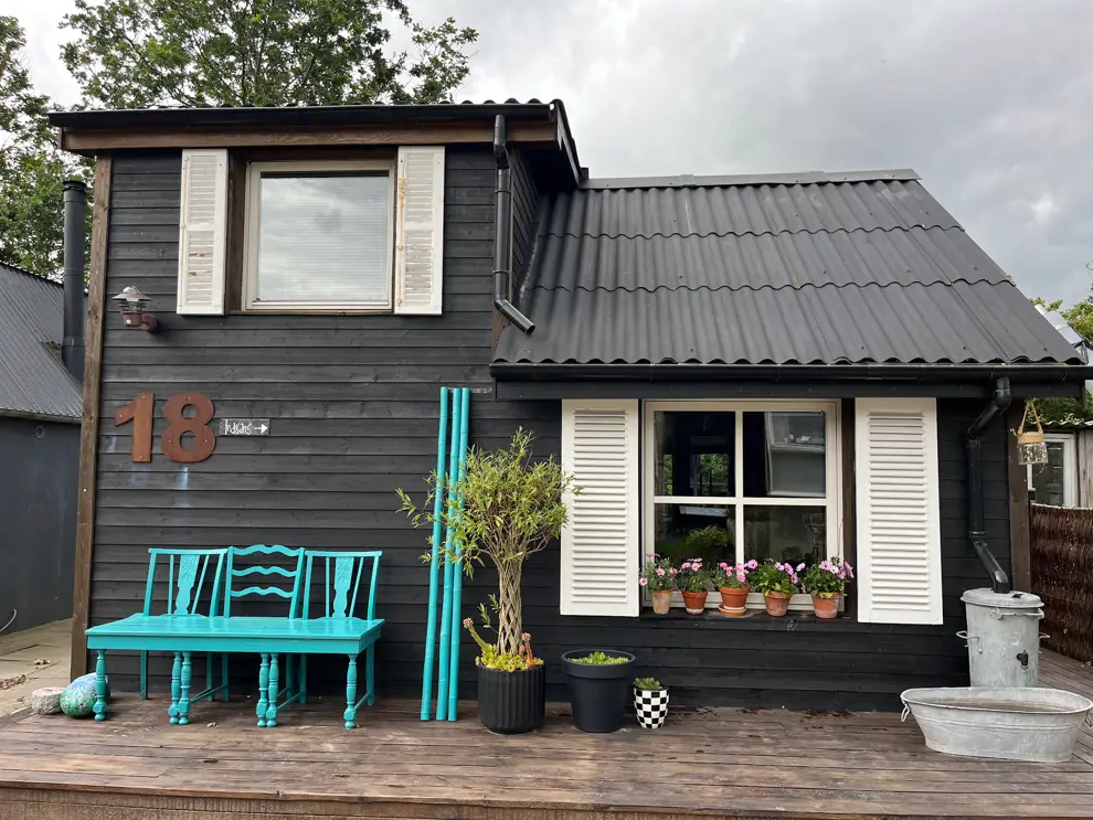 Schwarze Holzhütte mit türkiser Bank in Fjordbyen in Aalborg