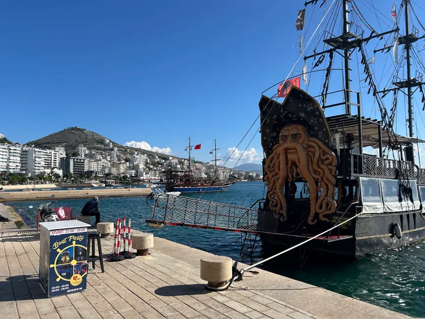 Ausflugsboot im Stil eines Piratenschiffs im Hafen von Saranda, im Hintergrund die Stadt am Hang