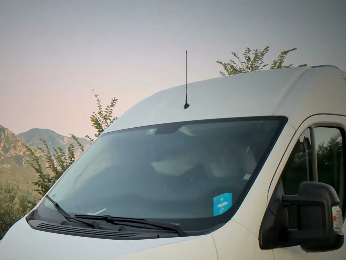 Unser Camper von vorn in der Abenddämmerung, dahinter Berge und Büsche