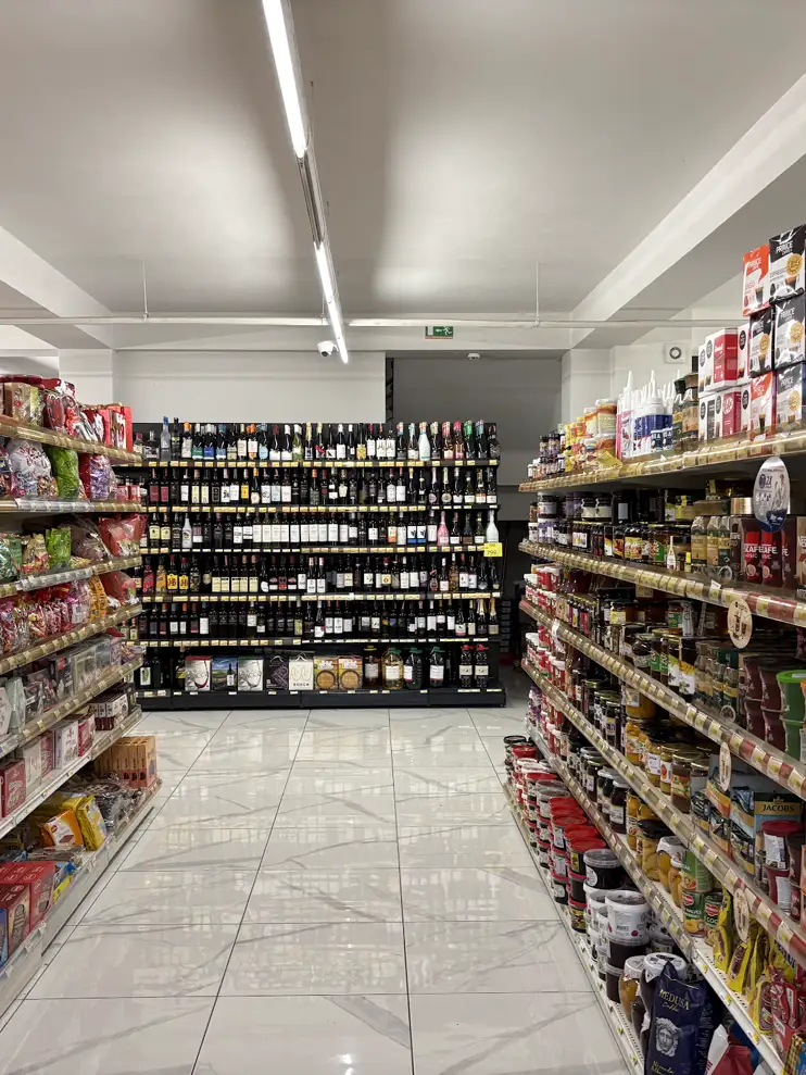 Gang in einem albanischen Supermarkt mit vollen Regalen, im Hintergrund eine Weinwand