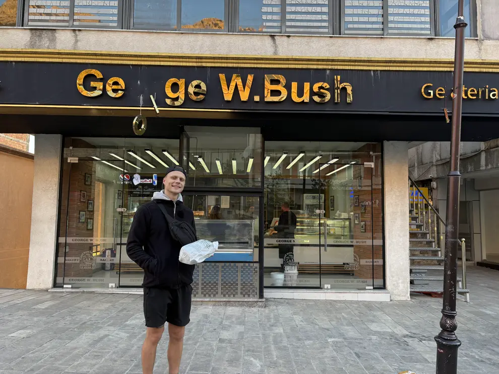 Mark mit einer Tüte Brot vor der Bäckerei George W. Bush in Kruja