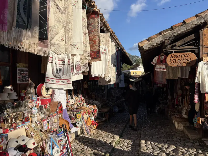 Gasse im Basar von Kruja mit Stickereien, Trachten, Filzmützen und Souvenirs an den Holzbuden