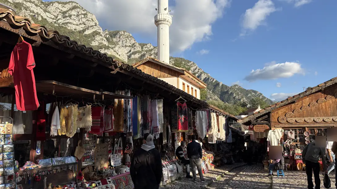 Alter Basar von Kruja mit Holzdächern, Textilständen, einem Minarett und den Bergen im Hintergrund