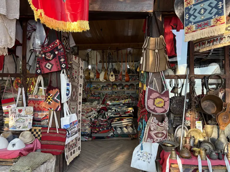 Laden im Basar von Kruja mit gewebten Taschen, Teppichen, Kupfergeschirr und Saiteninstrumenten