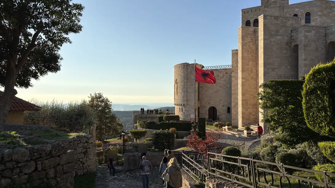 Weg durch die Festung von Kruja zum Skanderbeg-Museum mit albanischer Flagge in der Abendsonne