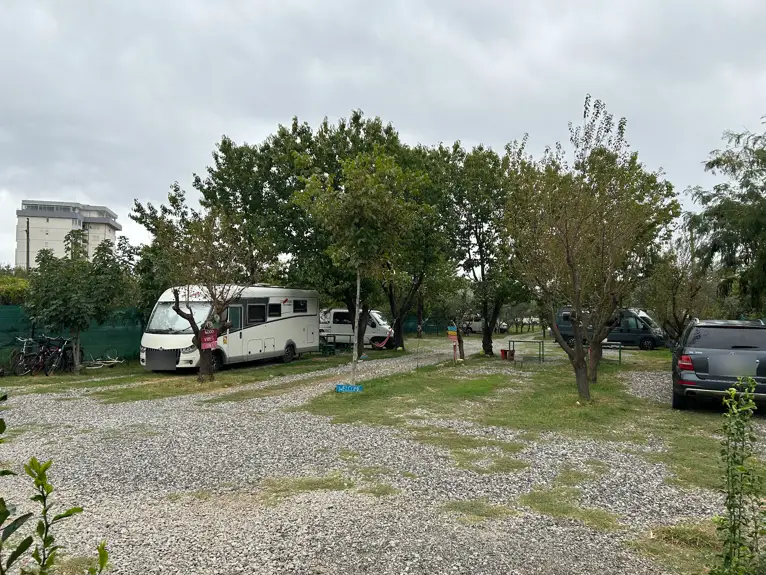 Camping Bandula in Shkodra mit Wohnmobilen zwischen Obst- und Olivenbäumen auf Schotterflächen
