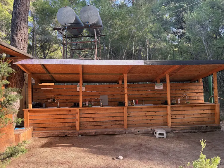Überdachte Außenküche aus Holz mit Spülbecken und Wassertanks auf dem Eco Camping Valona