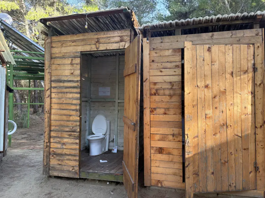 Toiletten- und Duschhäuschen aus Holz mit offener Tür auf dem Eco Camping Valona