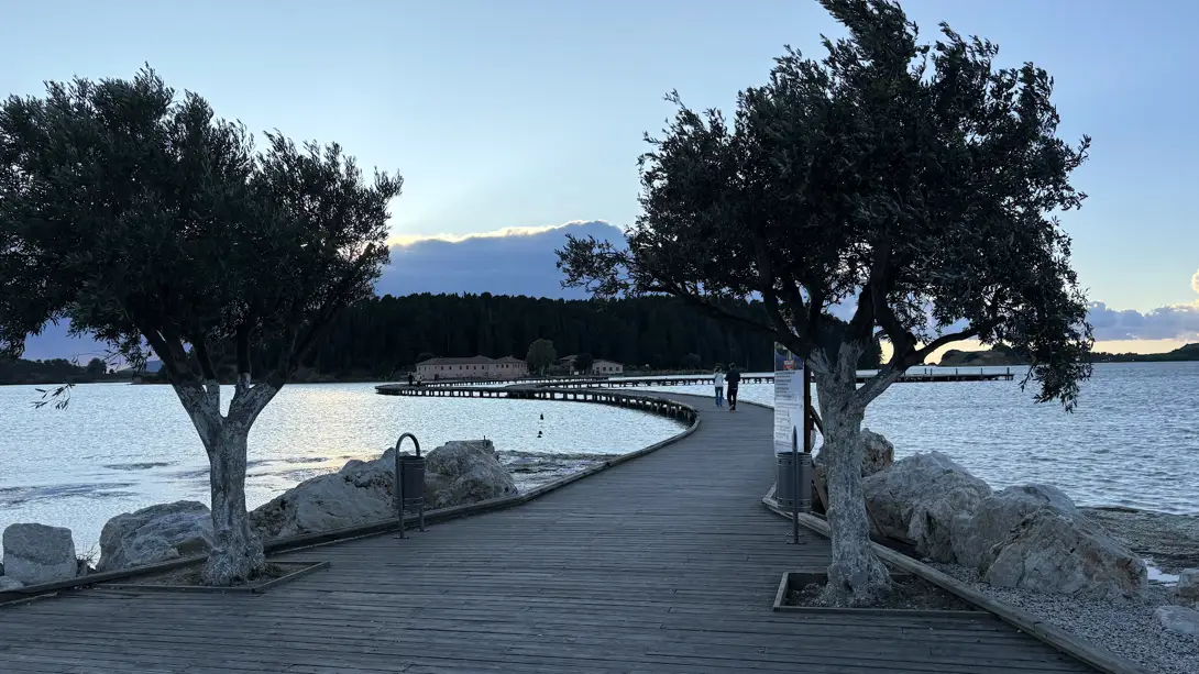 Holzsteg über das Wasser der Lagune zur Klosterinsel Zvërnec bei Vlora in der Abenddämmerung