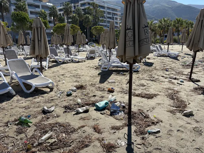 Zugeklappte Sonnenschirme und Liegen am Strand von Vlora, dazwischen Plastikflaschen und Müll