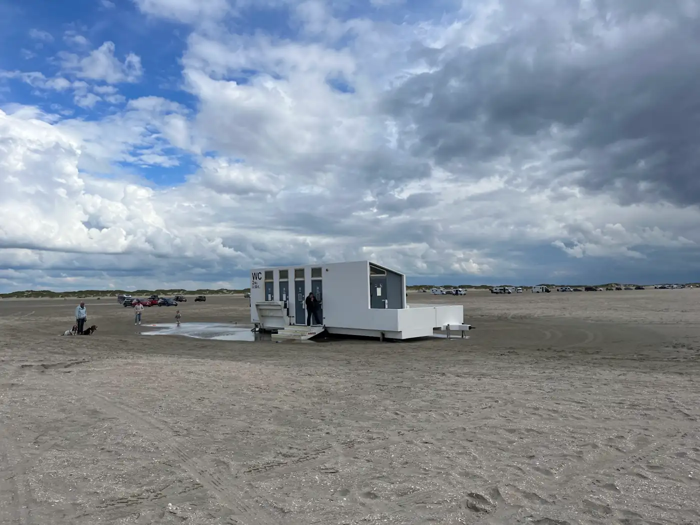 Mobiles weißes Toilettenhäuschen mit Gebührenschild mitten auf dem Strand von Rømø