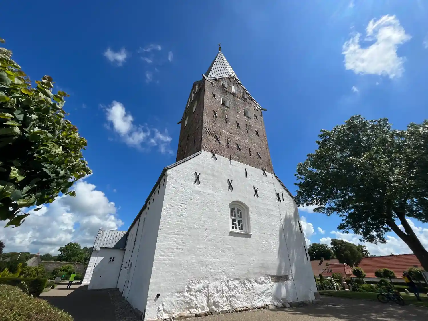 Weiß gekalkte Møgeltønder Kirche mit Backsteinturm unter blauem Himmel