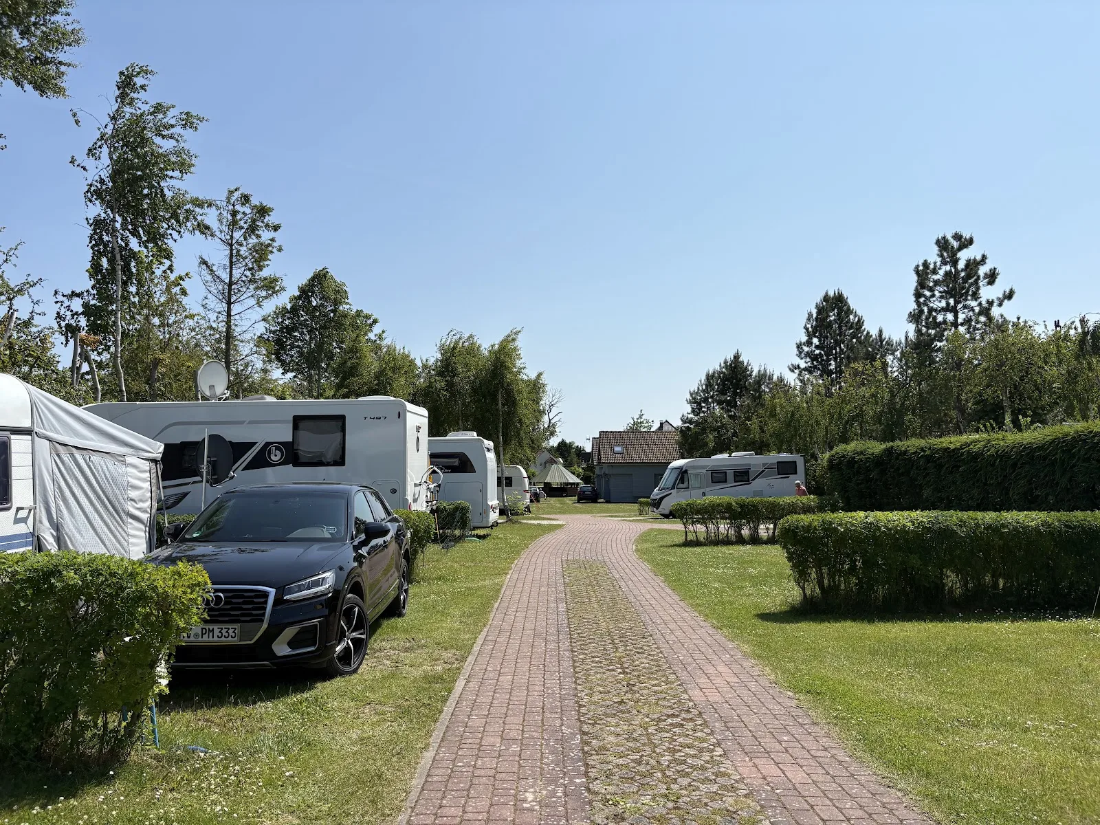 Parzellen auf Camping Pomona mit Hecken-Trennung und geparkten Wohnmobilen