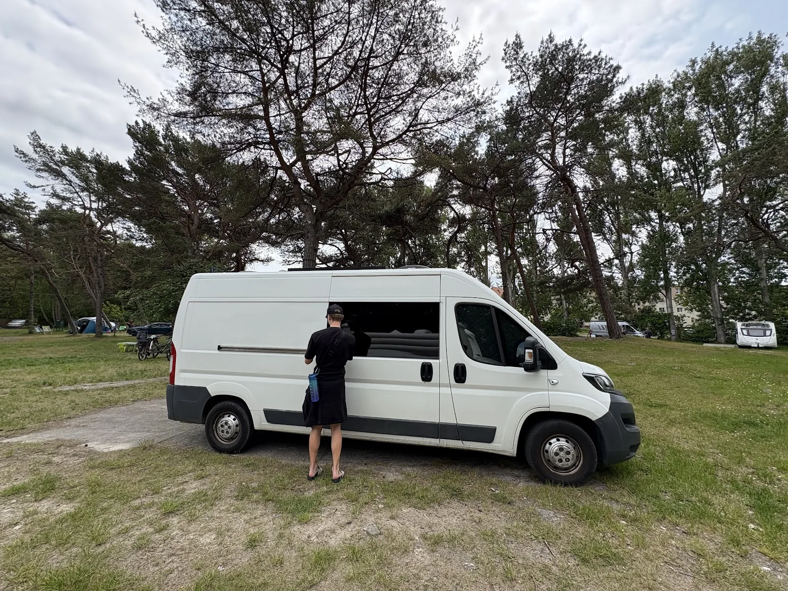 Wohnmobil auf dem Stellplatz Camp Hel im Waldstück nahe der Stadt