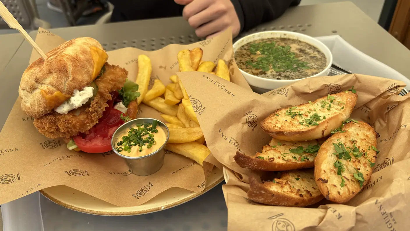 Fischburger mit Pommes, Fischsuppe und Knoblauchbrot auf dem Tisch der Fischbraterei Kergulena in Niechorze