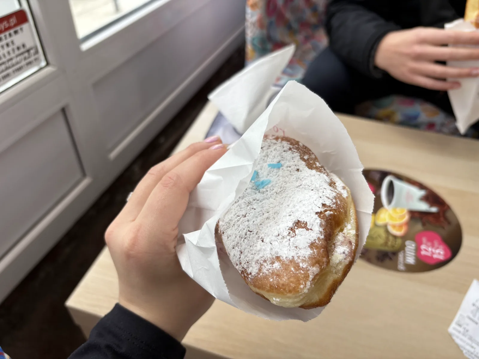 Frisch gefüllter polnischer Pączek mit Puderzucker in der Hand, typisches Camper-Naschwerk aus Schreiberhau