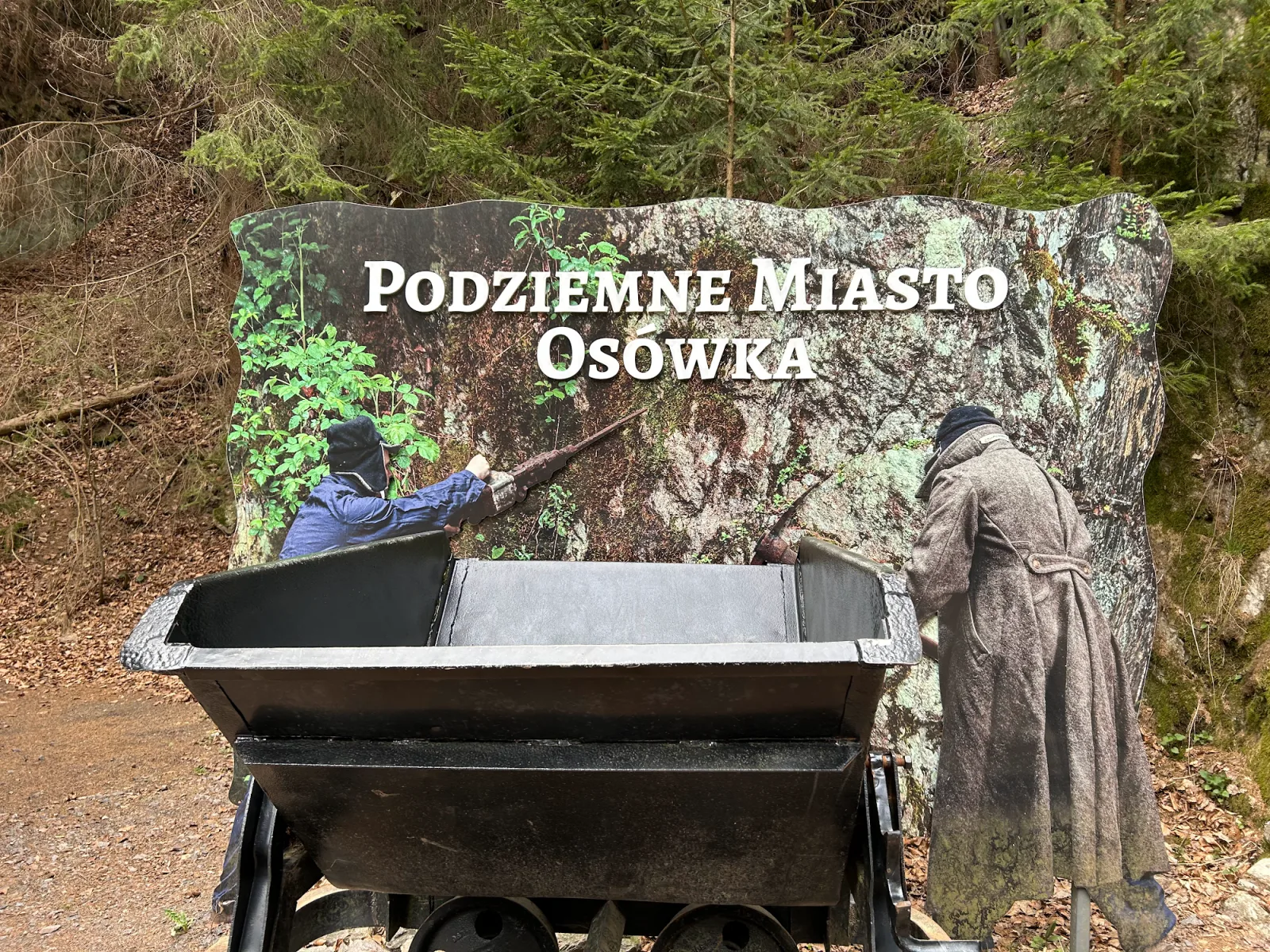 Projekt Riese Osówka Wandbild mit Zwangsarbeiter-Skulpturen und Original-Lore am Tunneleingang