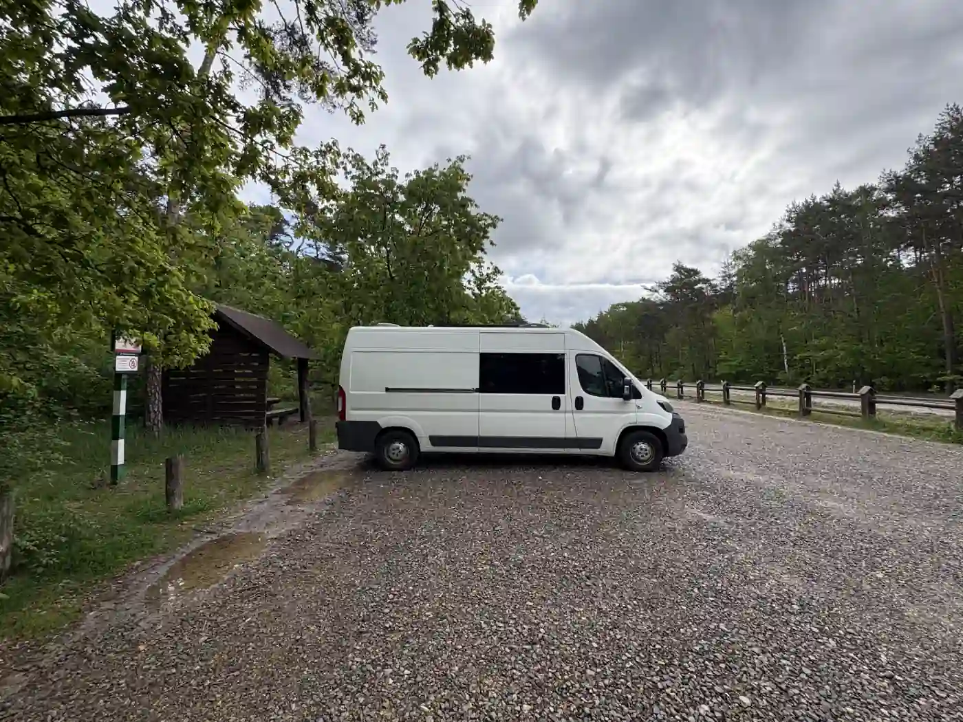 Kastenwagen auf einem Rastplatz am Waldrand in Polen neben einer Holzhütte