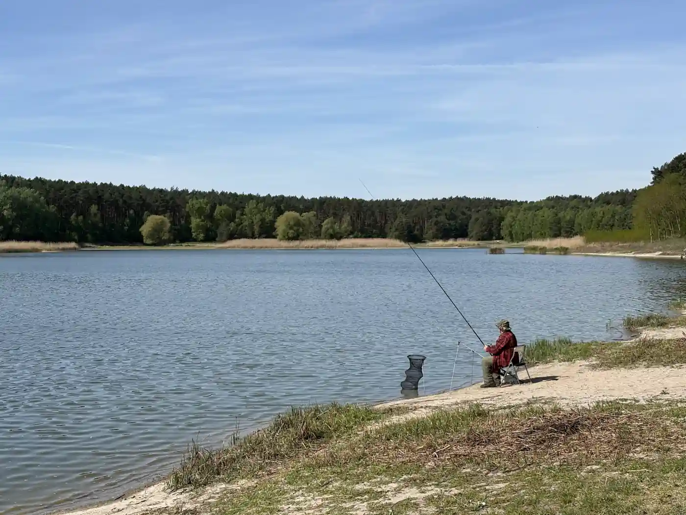Angler am Ufer eines Waldsees in Polen an einem sonnigen Tag