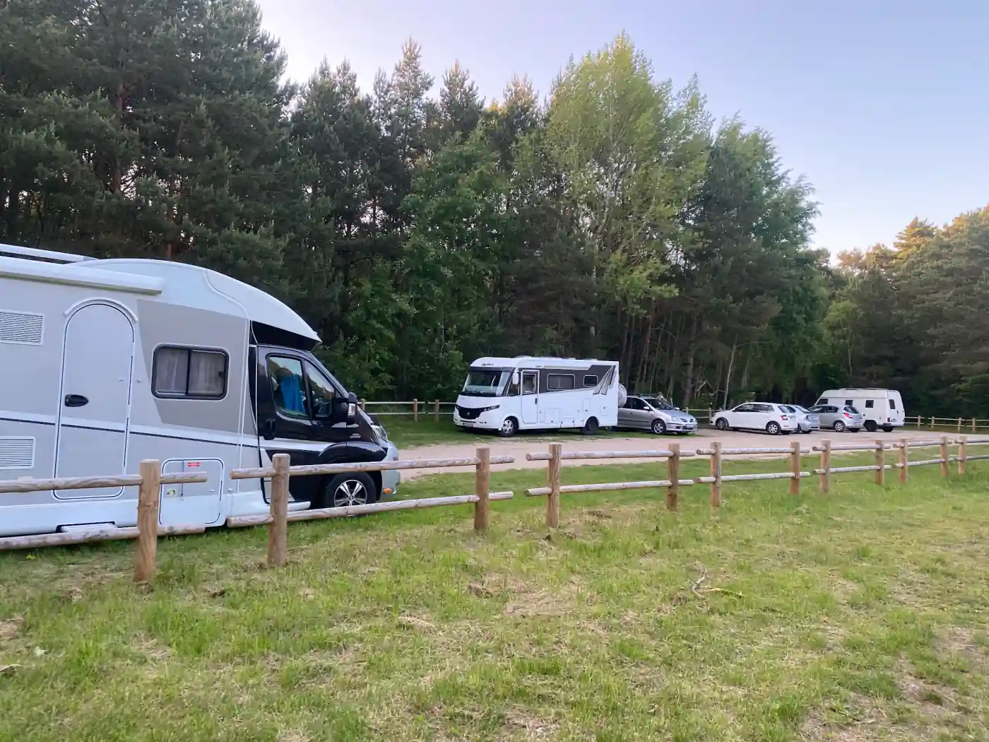 Wohnmobile und Autos auf einem Parkplatz am Wald in Polen