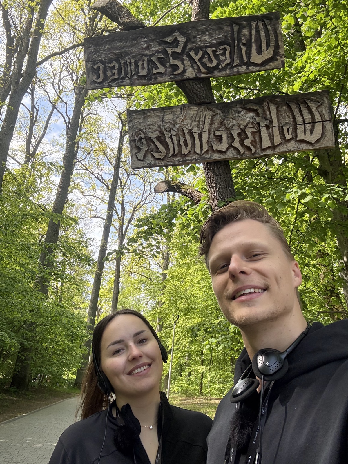 Mark und Lara Lehmann vor dem Wolfsschanze-Holzschild in Gierłoż nach der Anfahrt durch die Masuren
