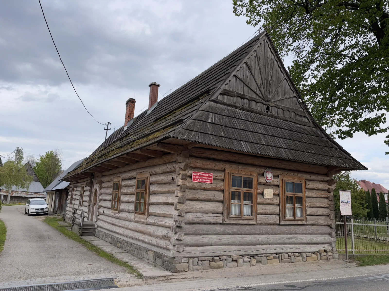 Traditionelles Goralen-Holzhaus in Chochołów bei Zakopane mit Schindeldach und Bibliothek-Beschilderung