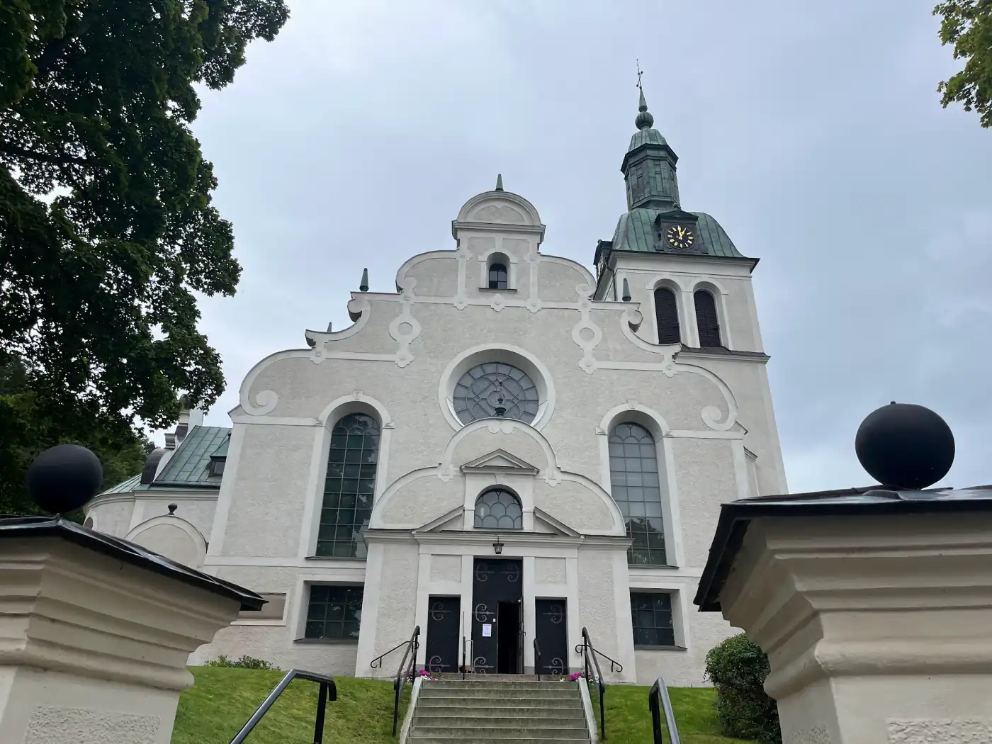 Weiße Fassade der Kirche von Gränna mit geschwungenem Giebel und grünem Turmdach