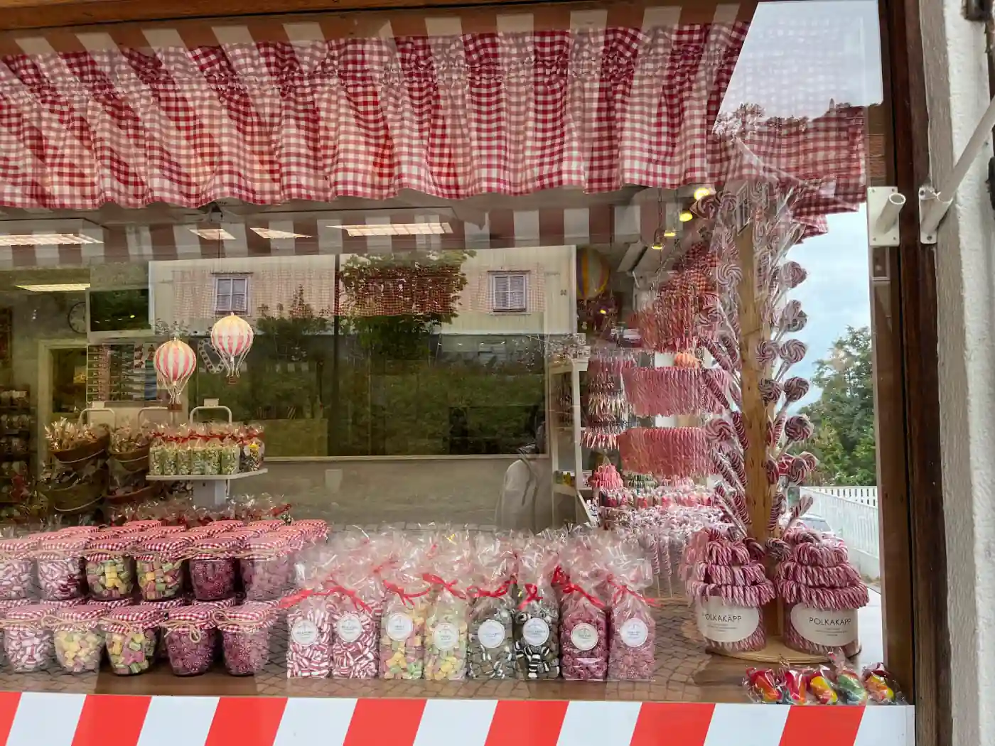 Schaufenster einer Polkagris-Konditorei in Gränna mit rot-weißen Zuckerstangen und Tüten