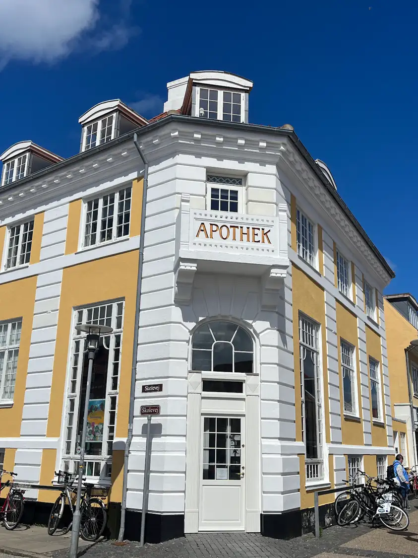 Das gelb-weiße Apotheken-Eckhaus in der Innenstadt von Skagen unter blauem Himmel