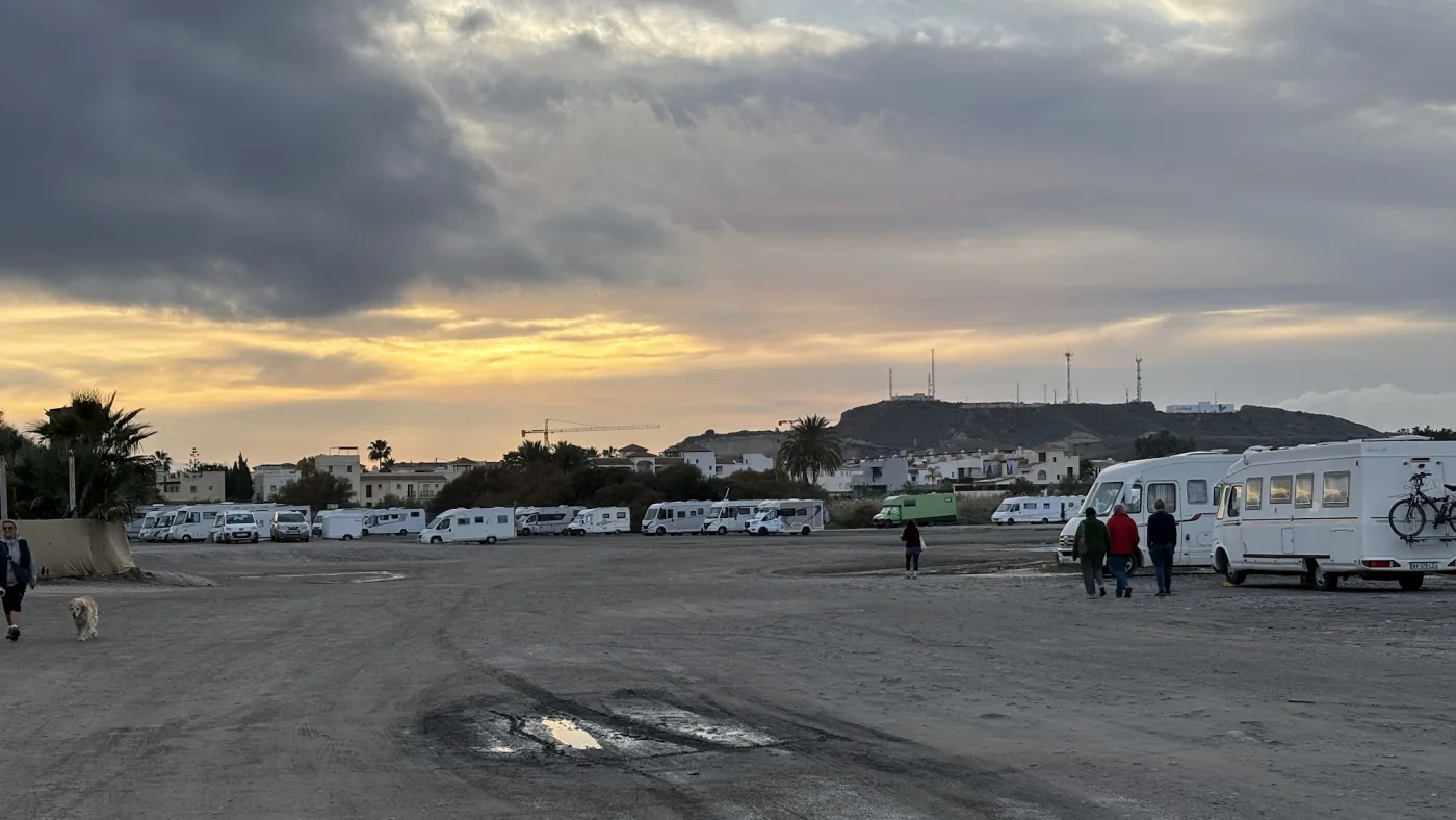 Große Schotterfläche an der Costa de Almería bei Sonnenuntergang, am Rand stehen zahlreiche Wohnmobile