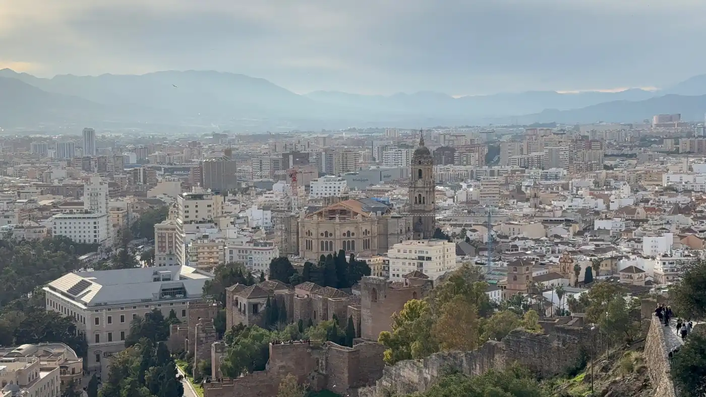 Blick über die Dächer und die Kathedrale von Málaga bis zu den Bergen im Hintergrund an einem diesigen Wintertag