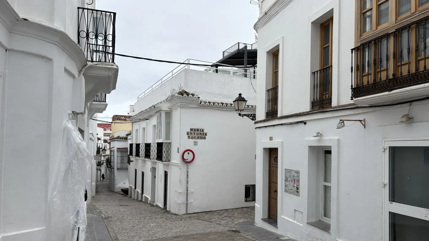 Menschenleere weiß getünchte Gasse in einer andalusischen Altstadt mit geschlossenen Läden