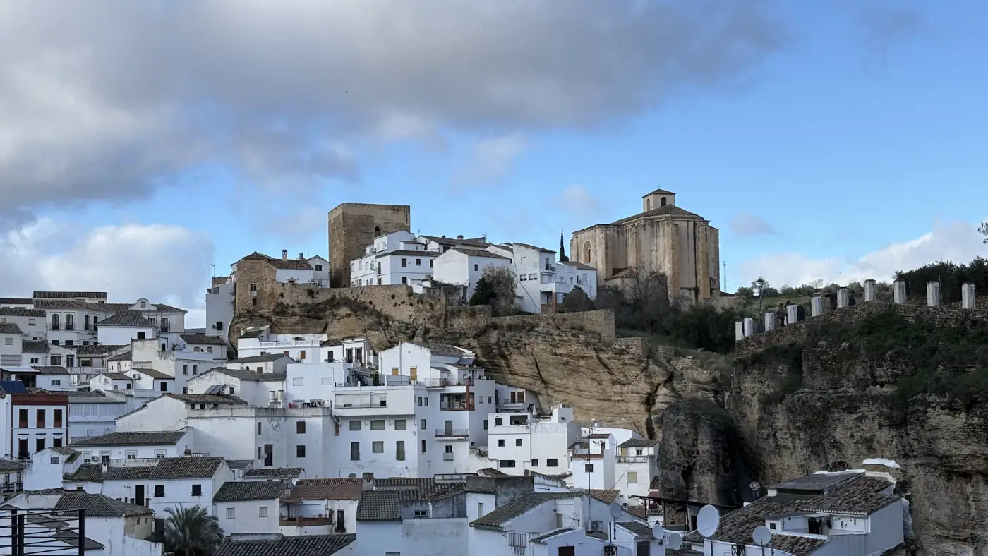 Panorama eines weißen andalusischen Dorfes mit Burg auf dem Felsen und weiß getünchten Häusern im Tal
