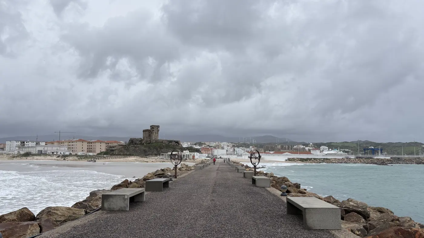 Damm zur Isleta de Tarifa unter einer schweren Wolkenfront, links und rechts aufgewühltes Wasser