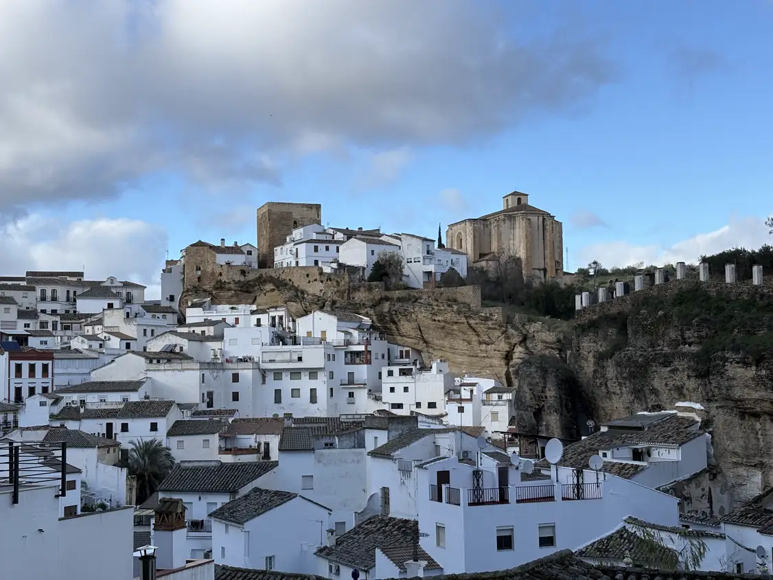 Blick vom Mirador del Carmen über die weißen Häuser von Setenil de las Bodegas hinauf zu Burgturm und Kirche