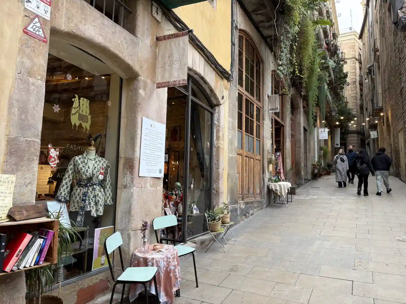 Kleine Läden und Cafétische in einer Altstadtgasse von Barcelona