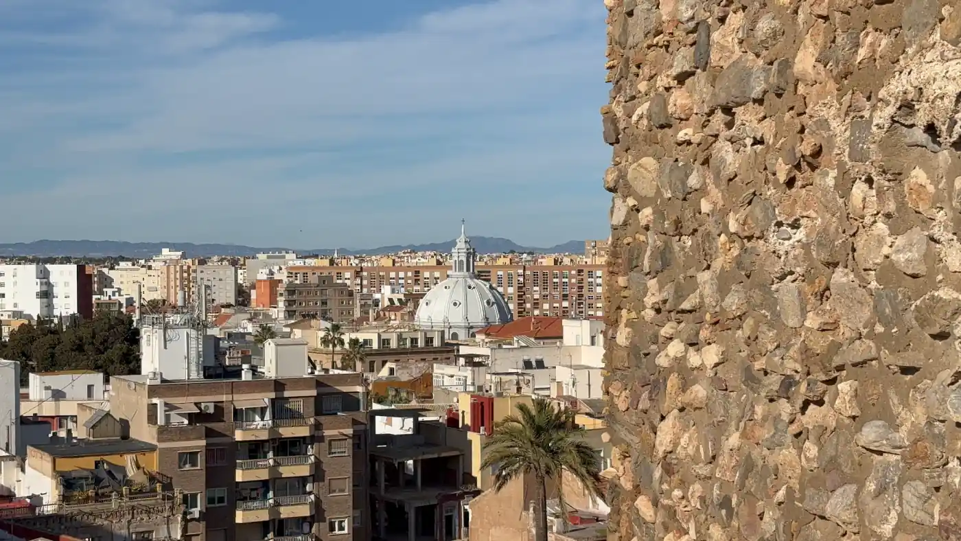 Blick über die Dächer von Cartagena auf eine graue Kirchenkuppel zwischen Wohnhäusern