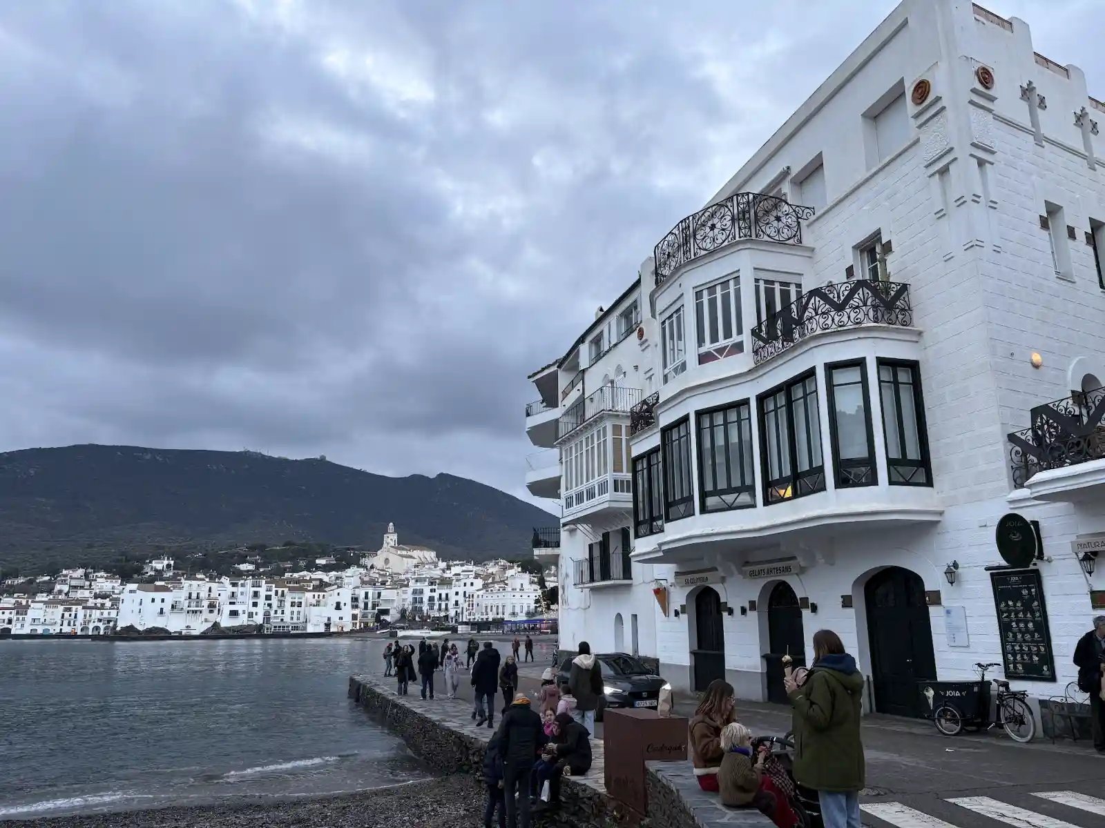 Weiße Häuser und Uferpromenade von Cadaqués an der Costa Brava mit Blick auf die Kirche