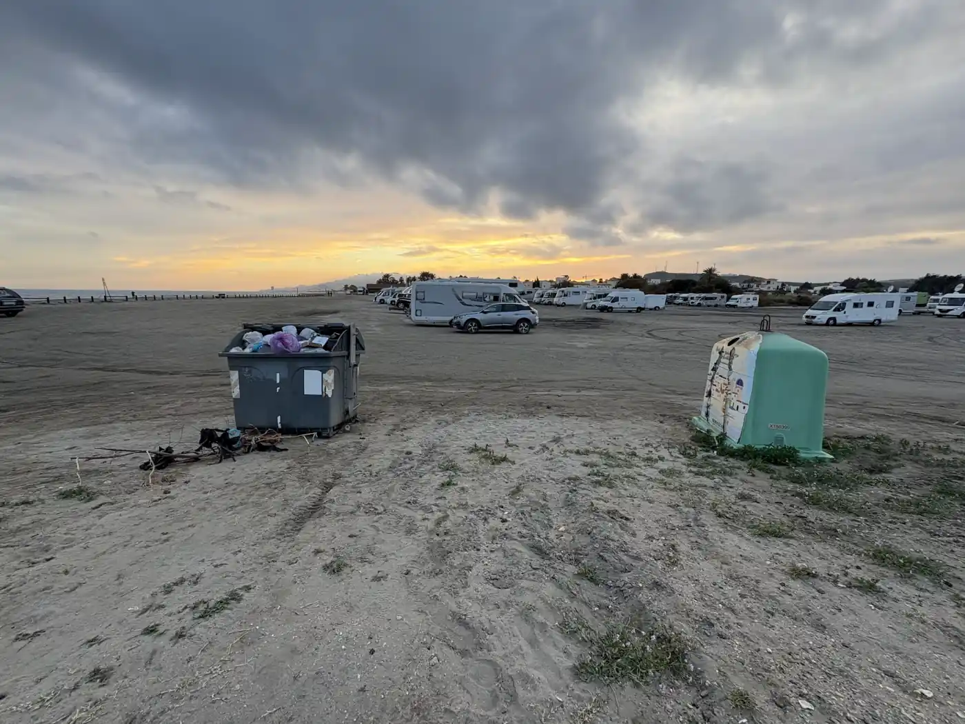 Müllcontainer auf einem Wohnmobil-Parkplatz am Meer in Spanien bei Sonnenuntergang